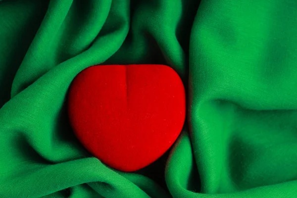 Caja de joyas roja regalo en forma de corazón en tela verde tela ondulada — Foto de Stock