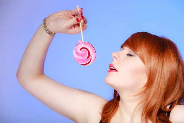 Сексуальная молодая женщина с конфетами. Рыжеволосая девушка ест сладкий леденец — стоковое фото