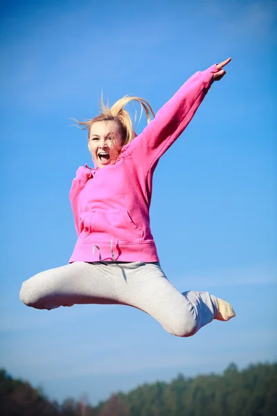 Cheerful woman teenage girl in tracksuit jumping showing outdoor — Stock Photo, Image