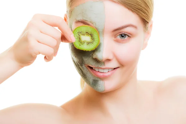 Woman in clay mask on face covering eye with kiwi — Stock Photo, Image