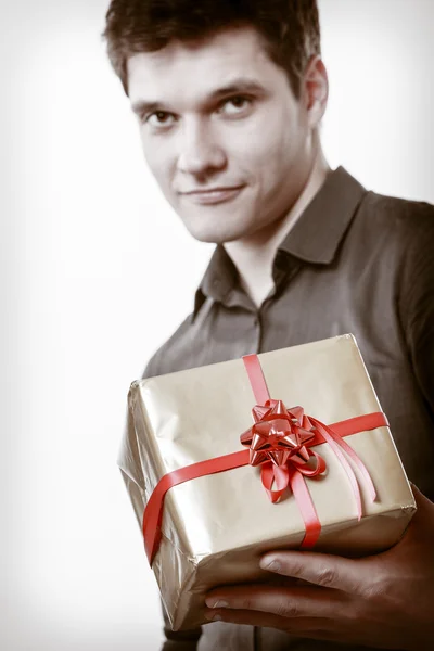 Svátek. muž dává zlaté dárkové krabičce s mašlí — Stock fotografie