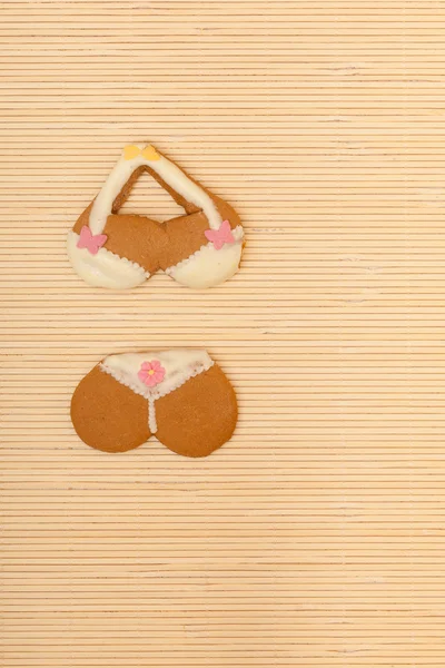 Yellow pink bikini shape gingerbread cake cookie on bamboo mat — Stock Photo, Image