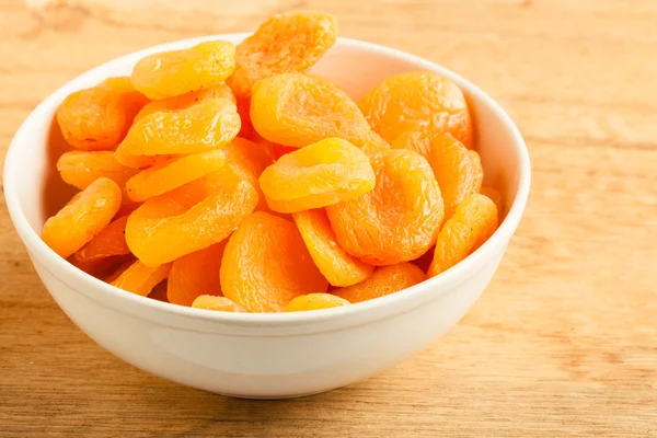 Bowl of dried apricots on wooden table background. — Stock Photo, Image