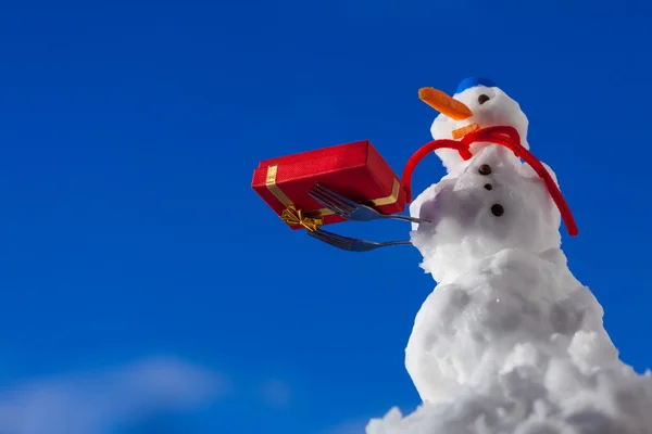 Маленький счастливый снеговик с рождественской подарочной коробкой на открытом воздухе. Зимний сезон . — стоковое фото
