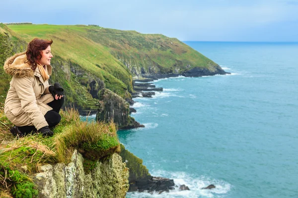 Kvinna sitter på rock klippa ser att havet Co cork Irland — Stockfoto