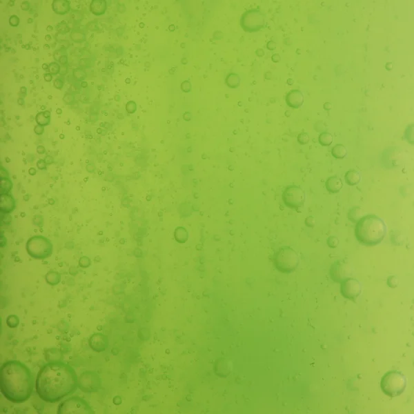 Tekuté mýdlové bubliny zelené pozadí — Stock fotografie