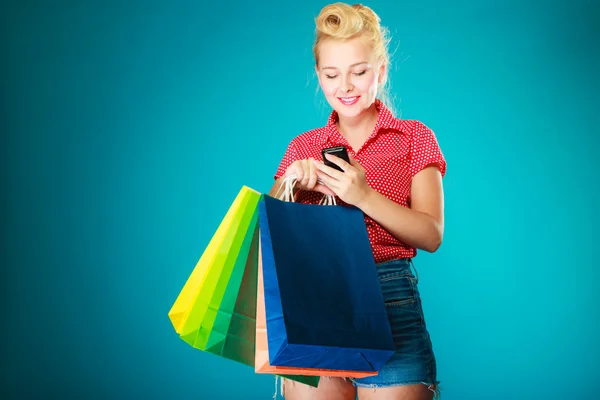 Pinup ragazza con borse della spesa sms sul telefono — Foto Stock