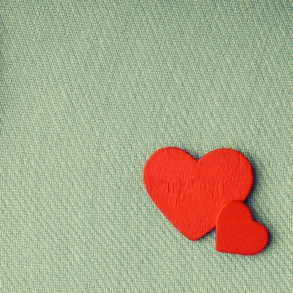 Red wooden decorative hearts on green cloth background. Royalty Free Stock Images