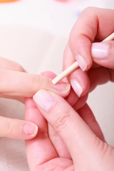 Kosmetikerin reinigt Nagelhaut Hände mit Kosmetikstick. Schönheitssalon — Stockfoto