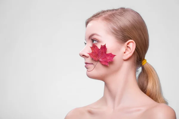 Skin care. Portrait of young woman girl with red maple leaf. — Stock Photo, Image