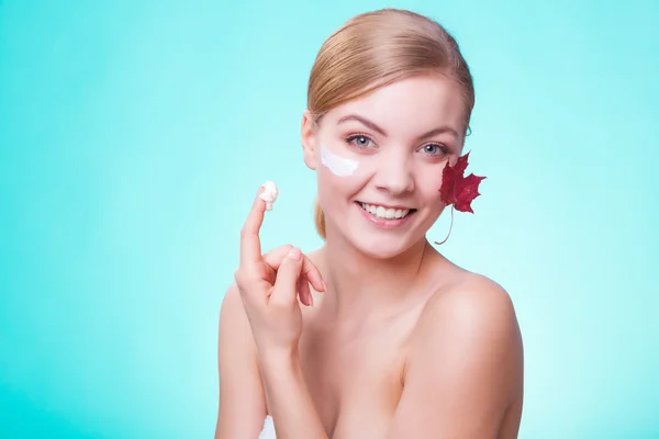 Huidverzorging. Gezicht van jonge vrouw meisje met rode esdoorn blad. — Stockfoto