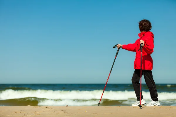 Nordic walking. Kobieta wędrująca po plaży. — Zdjęcie stockowe