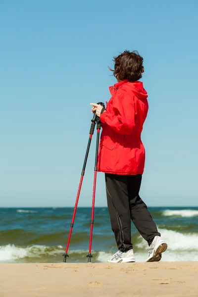 Nordic walking. Wandelende vrouw op het strand. — Stockfoto