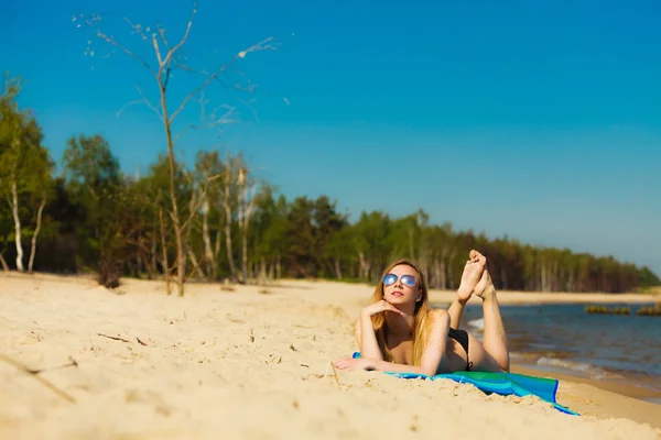 Jenta i bikini soler seg på stranda. – stockfoto