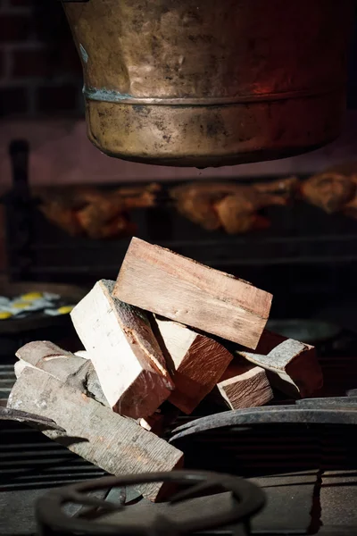 Old hearth with pile of fire wood and pot. Indoor. — Stock Photo, Image