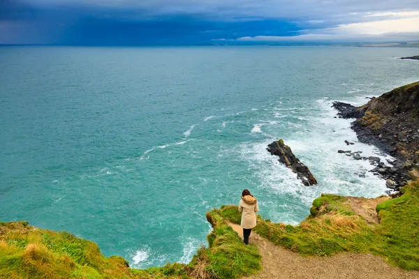 Donna in piedi sulla scogliera rocciosa vicino all'oceano Co. Cork Irlanda — Foto Stock