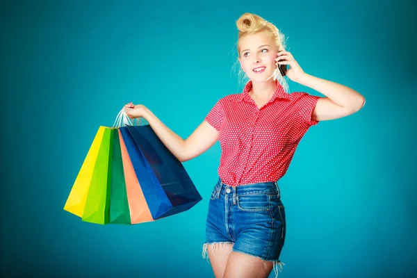 Pinup dívka s nákupními taškami volá na telefon — Stock fotografie