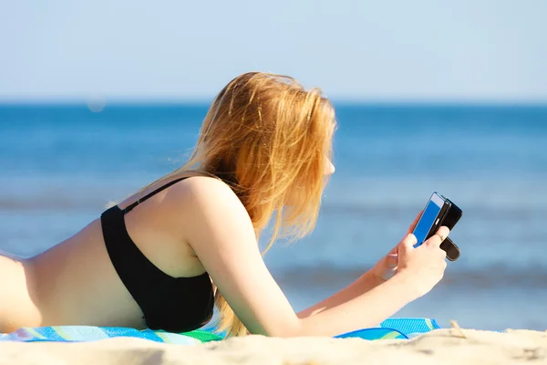 Summer vacation Girl with phone tanning on beach — Stock Photo, Image