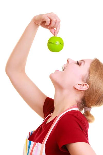 Funny housewife in kitchen apron trying to eat apple timer isolated — Stock Photo, Image
