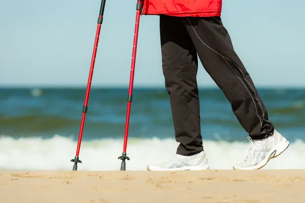 Caminar nórdico. Piernas femeninas senderismo en la playa. —  Fotos de Stock