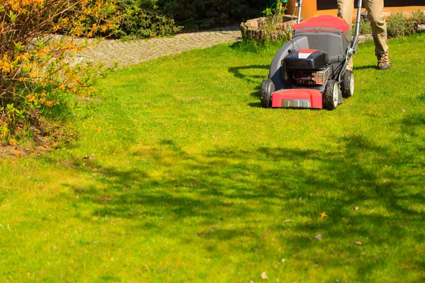 Mowing green lawn with red lawnmower — Stock Photo, Image