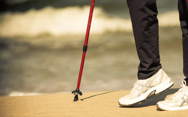 Caminar nórdico. Piernas femeninas senderismo en la playa. — Foto de Stock