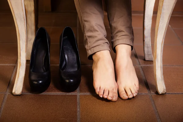 Nakna kvinnliga fötter under tabellen vintage. — Stockfoto