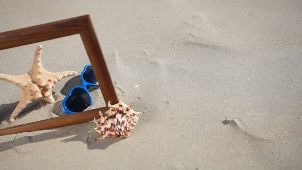 Concha, estrella de mar y gafas en marco de madera en la playa — Vídeos de Stock