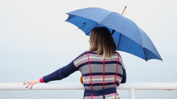 Femme avec un parapluie se tient et regarde la mer — Video