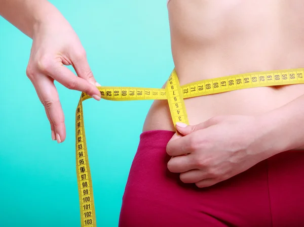 Fitness girl with measure tape measuring her waist — Stock Photo, Image