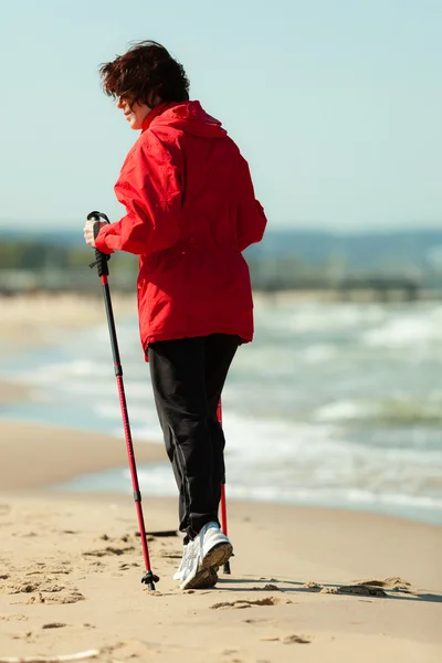 Nordic walking. Kobieta wędrująca po plaży. — Zdjęcie stockowe