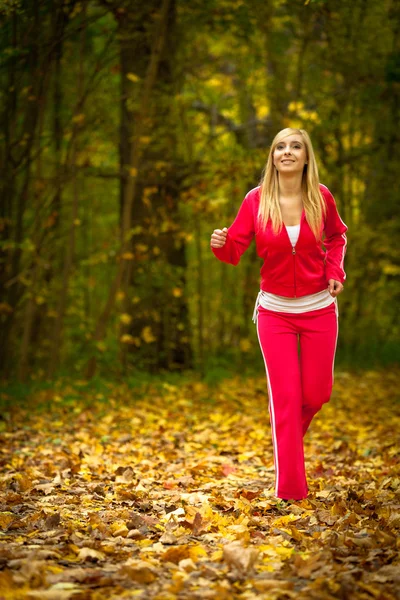 Blonde young woman running jogging in autumn fall forest park — Stock Photo, Image