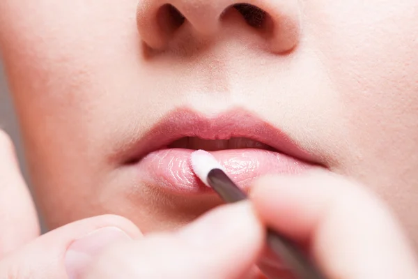 Mädchen trägt Lipgloss-Lippenstift auf die Lippen auf. — Stockfoto