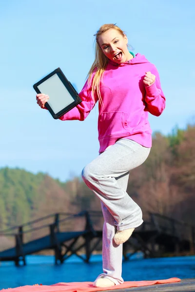 Teenage girl in pink tracksuit showing blank tablet outdoor — Stock Photo, Image