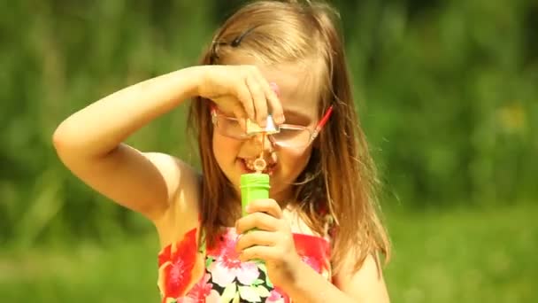 Child  blowing a soap bubbles on the meadow or in the park. — Stock Video