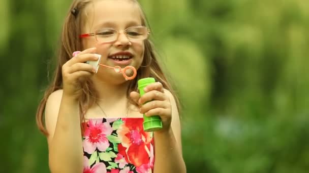 Child  blowing a soap bubbles on the meadow or in the park. — Stock Video