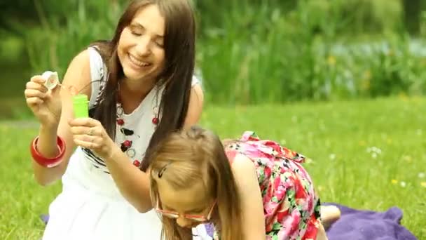 Jovem mulher e menina soprando uma bolhas de sabão — Vídeo de Stock