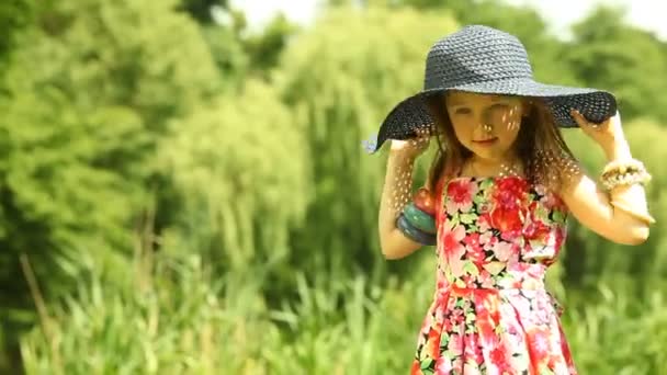 Little girl  in  black straw hat on the meadow or in the park outdoor. — Stock Video