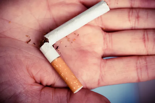 Broken cigarette on hand. — Stock Photo, Image