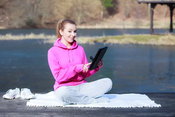 Sport teenage girl using tablet touchpad on pier — Stock Photo, Image