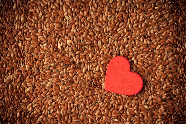 Semillas de lino de linaza como fondo alimentario y corazón rojo — Foto de Stock
