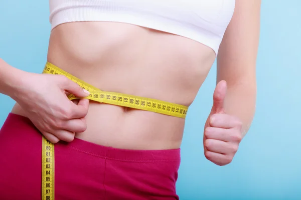 Fitness woman with measure tape measuring her waist — Stock Photo, Image