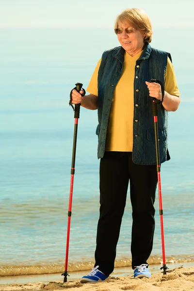 Aktive Seniorin beim Nordic Walking am Strand — Stockfoto