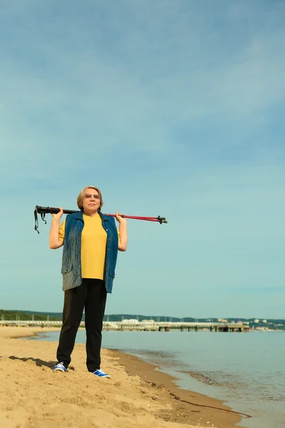Actieve vrouw senior nordic wandelen op een strand — Stockfoto