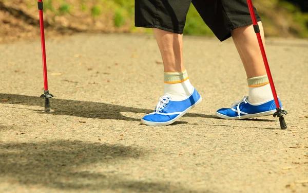 Jambes âgées actives en baskets marche nordique dans un parc . — Photo