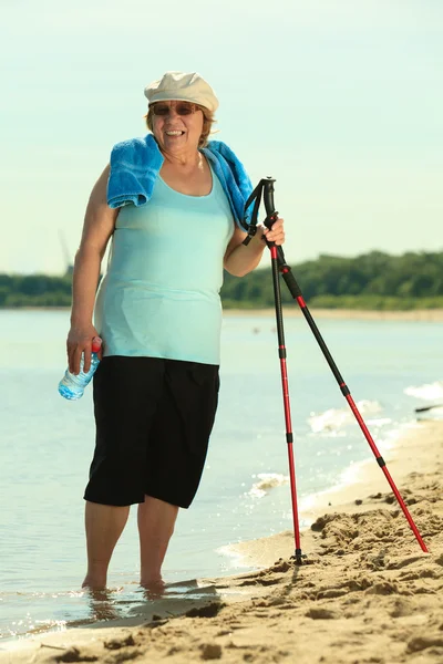 Mujer activa sénior nórdico caminando en una playa —  Fotos de Stock