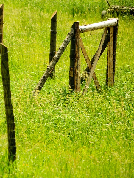 Houten, roestige hek op een groen, platteland gras — Stockfoto