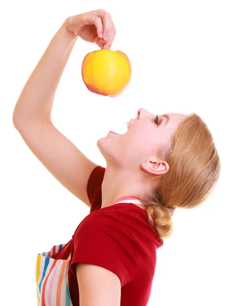 Roliga hemmafru i kök förkläde försöker äta äpple — Stockfoto