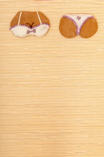 Yellow pink bikini shape gingerbread cake cookie on bamboo mat — Stock Photo, Image