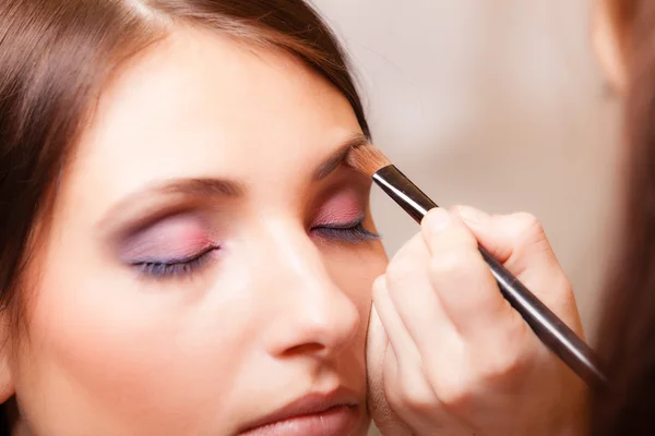 Artista de maquillaje aplicando con cepillo cosmético en la ceja de la mujer — Foto de Stock